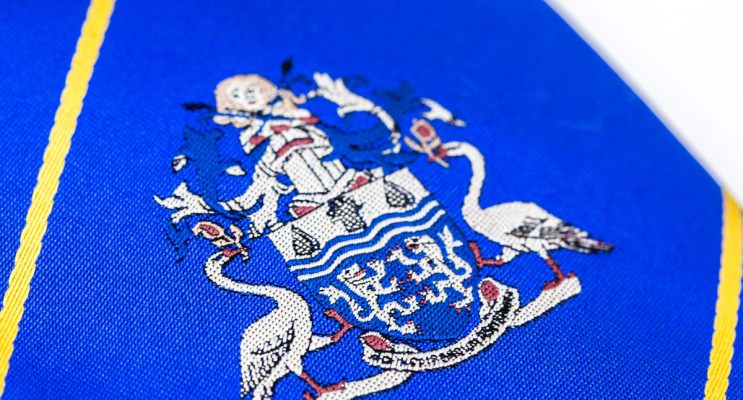 Close up of blue tie with embroidered logo