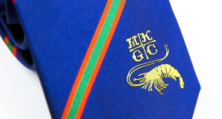 Close up of blue tie with gold embroidered logo