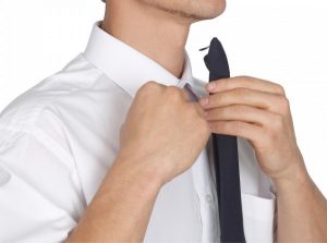 Man attaching clip on tie to his white shirt collar